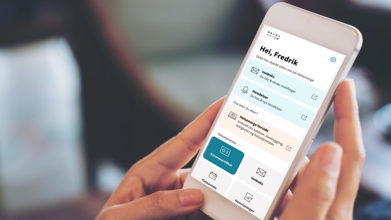 Bilde av hender som holder en mobiltelefon som vider Helsenorge-appen