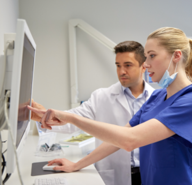 Bilde av to helsearbeidere som ser på en dataskjerm